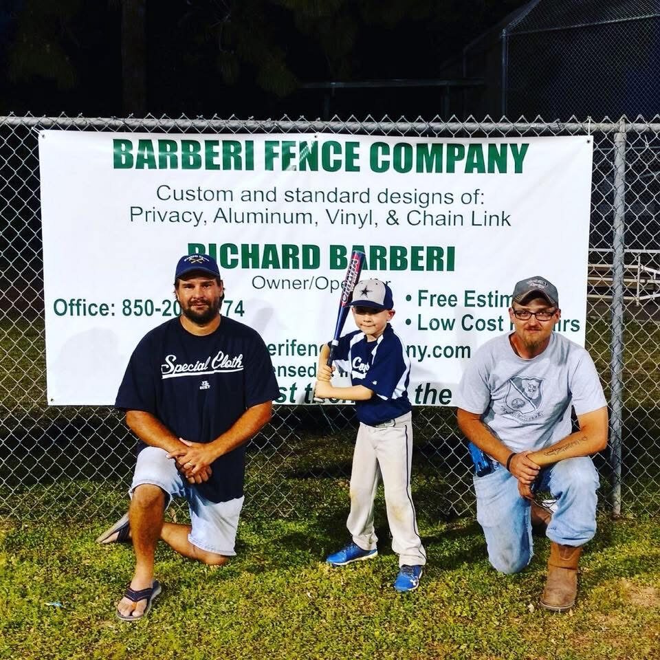 Rick Barberi with his son at a local ballpark in front of the Barberi Fence Company banner